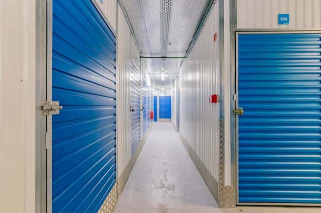 Corredor de unidades de self-storage com portas azuis.